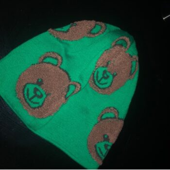 A green bear hat with brown bear faces knitted onto it on a black background